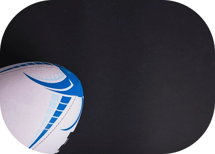 Close-up of a white rugby ball with blue geometric patterns on a black background. The ball is partially visible, creating a dynamic, sporty feel.